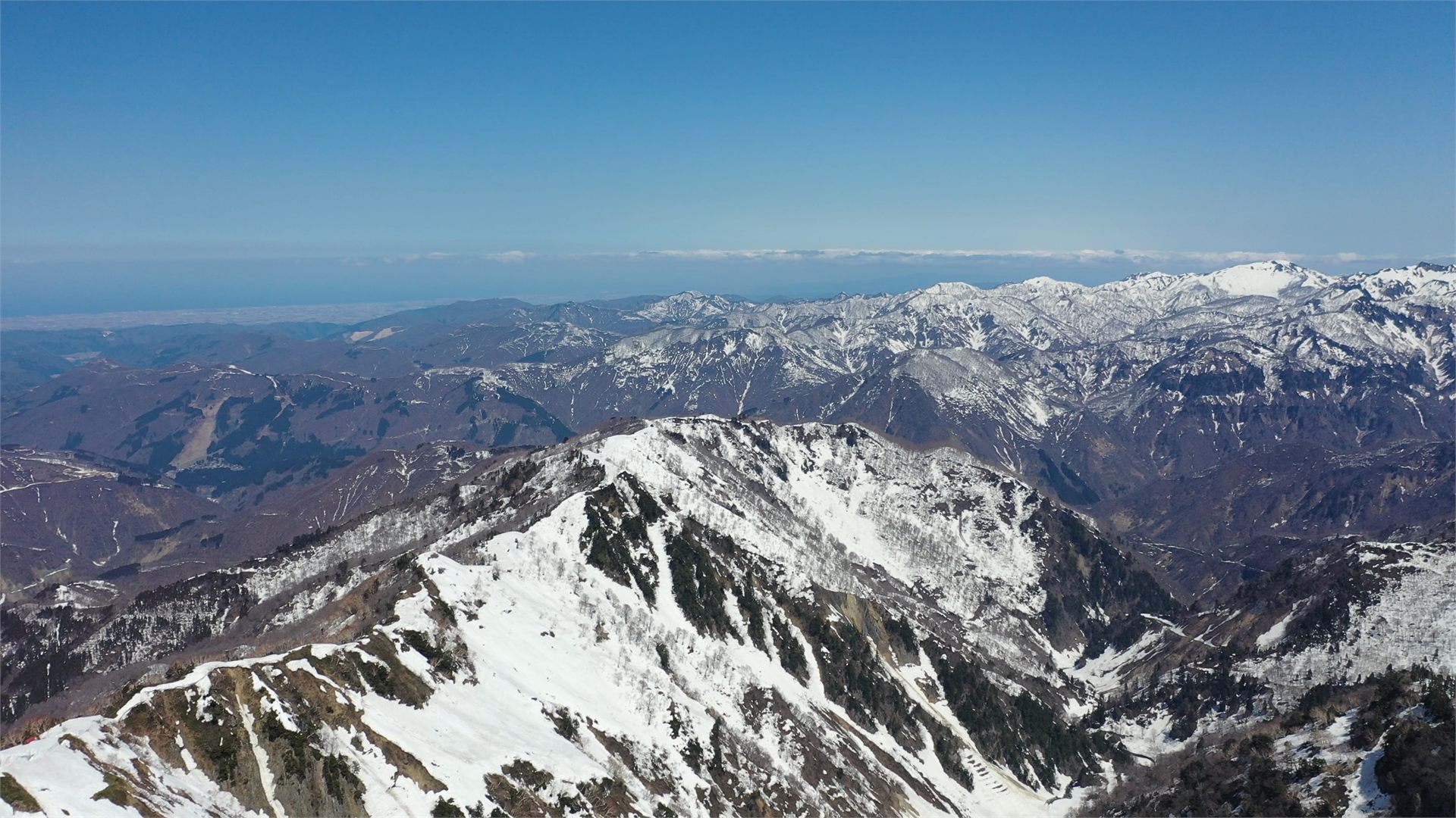 北部白山の残雪をまとった稜線の空撮